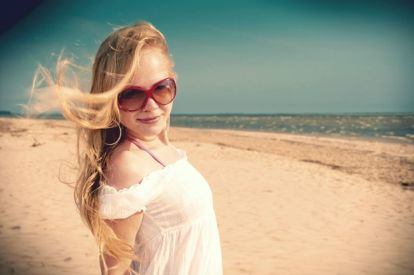 Eine junge Frau mit Sonnenbrille am Strand